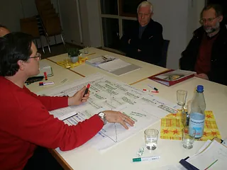 mehrere Menschen sitzen zu einer Besprechung am Tisch