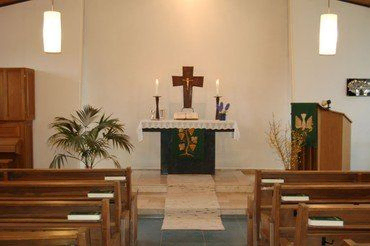 Schlichter Kirchenaltar mit Kreuz und Kerzen.