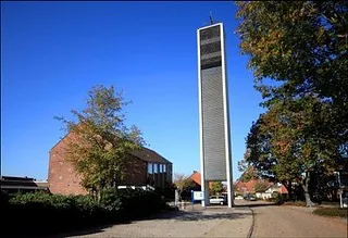 Glockenturm und Backsteingebäude unter blauem Himmel.