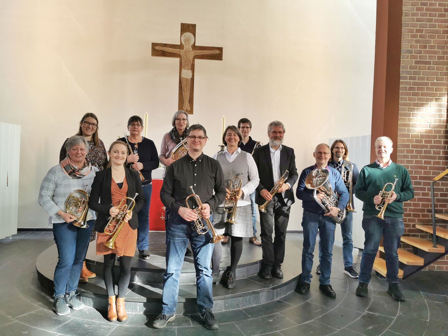  Eine Gruppe von Musikern steht in einer Kirche vor einem Kreuz.