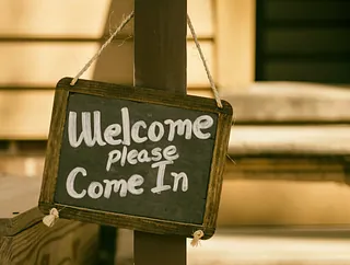Schild mit Aufschrift "Welcom, please come in" (zu deutsch Willkommen, komm herein