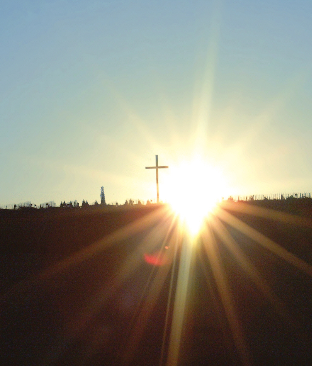 Kreuz auf einem Hügel im Gegenlicht der Sonne