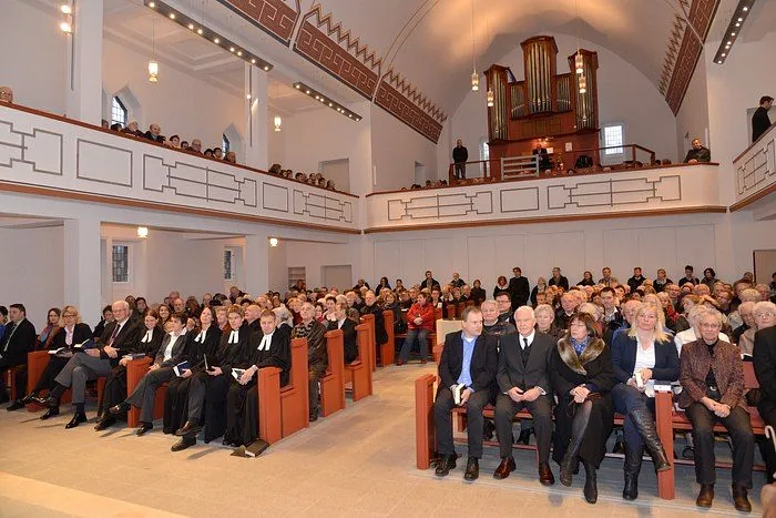 Kirchenschiff mit vollen Bänken, Empore und Orgel im Hintergrund.