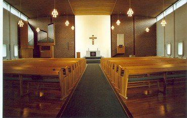 Innenansicht einer modernen Kirche mit Holzreihen und Altar.